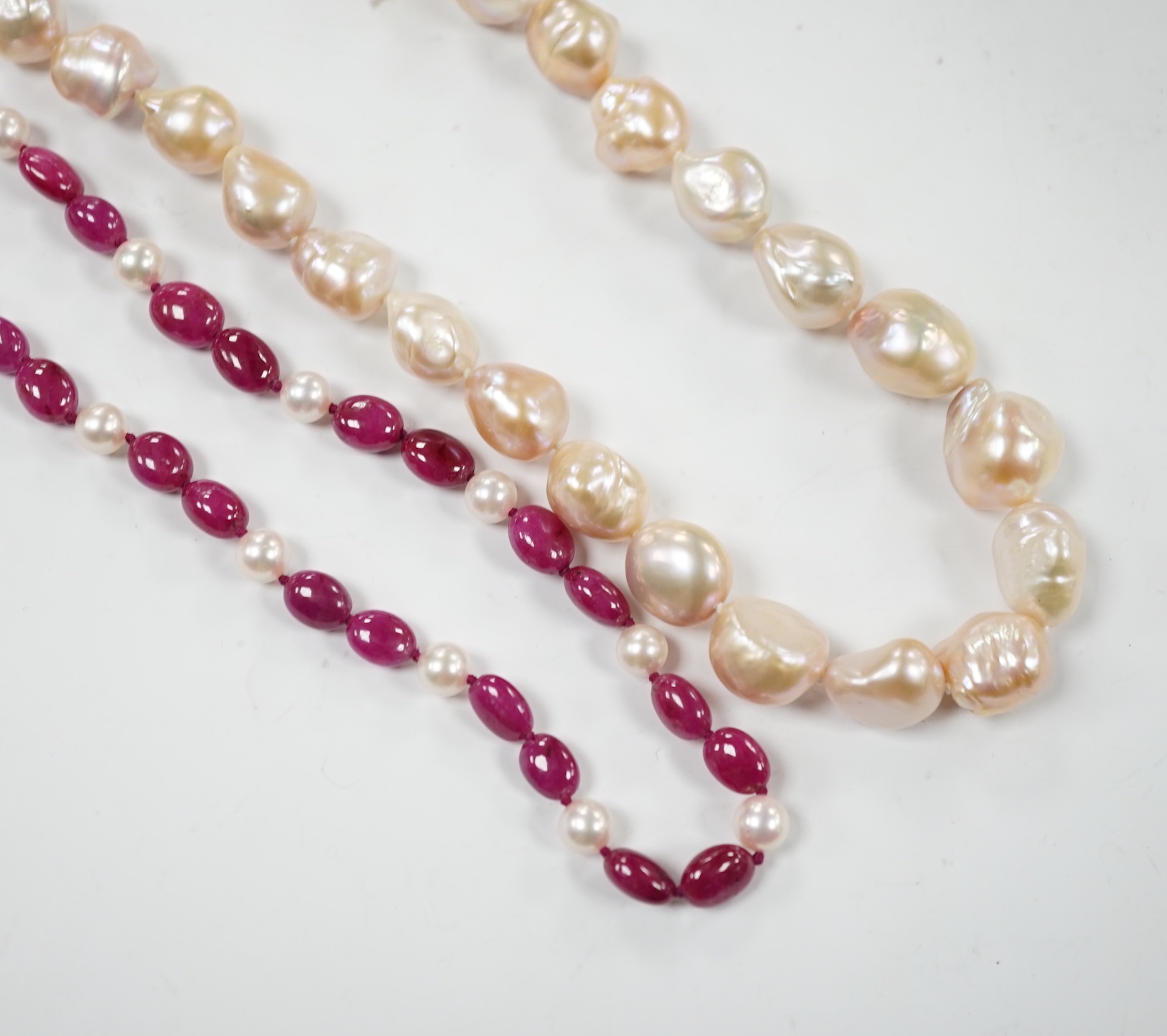 A modern cultured pearl and polished ruby? bead necklace, with two stone diamond chip set 750 clasp, 166cm and a modern baroque freshwater? pearl necklace with 925 clasp.